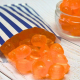 Orange coloured boiled sweets in a paper bag.