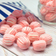 Pink and white striped soft crumbly sweet spilling out of a paper bag.