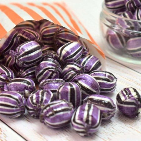 Purple & black striped blackcurrant and liquorice flavour boiled sweets in a paper bag.