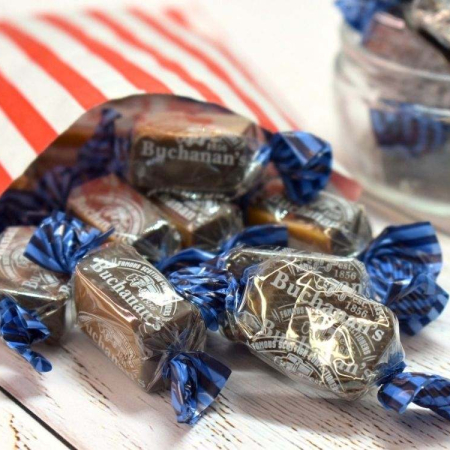 Wrapped buchanans of scotland dark chocolate italian creams spilling out of a paper bag.