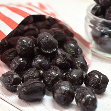 black sugar free cinnamon flavour boiled sweets in a paper bag.