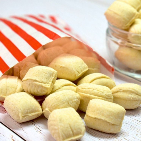 Cream coloured soft crumbly ginger flavoured sweet spilling out of a paper bag.