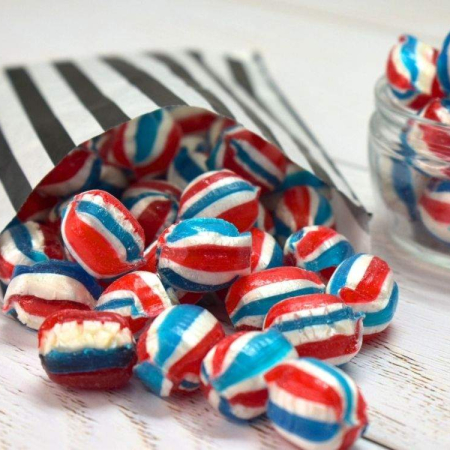 Blue, red and white striped rangers fc themed boiled sweets spilling out of a paper bag.