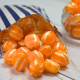 Orange and white striped iron brew humbugs spilling out a striped paper bag.