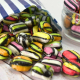 Colourful striped liquorice satin sweets spilling out of a paper bag.
