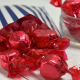 Red foil-wrapped Raspberry Ruffles sweets by Jamesons spilling from a blue and white striped paper bag.