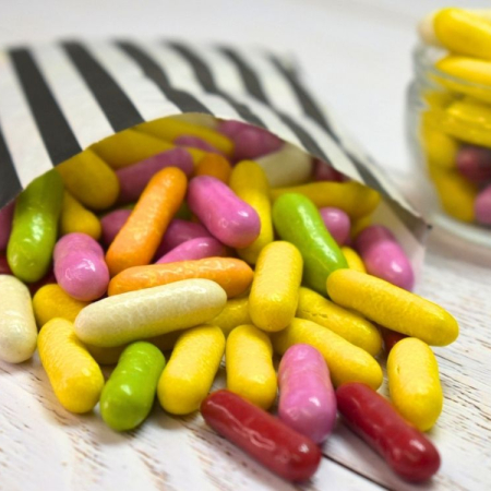 Multicoloured liquorice comfits sweets spilling from a black and white striped paper bag