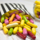 Multicoloured liquorice comfits sweets spilling from a black and white striped paper bag