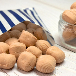 Coffee creams sweets from Ross's of Edinburgh spilling from a blue and white striped paper bag.
