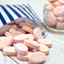 Ross's cinnamon flavoured oddfellows, small peach-pink sweets spilling out of a paper bag.