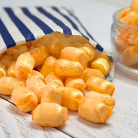 Orange Iron brew straws sweets spilling from a blue and white striped paper bag.