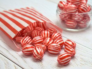 Red & white striped Aniseed flavour boiled sweets in a paper bag.