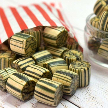 Brown and cream striped ginger rock sweets spilling from a red and white striped paper bag.