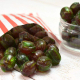 Green coloured apple flavour boiled sweets spilling out of a striped paper bag.