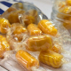 Wrapped sweet peanuts spilling from a blue and white striped paper bag.